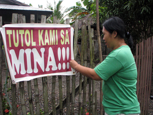 lady hanging sign in protest to mine in Philippines